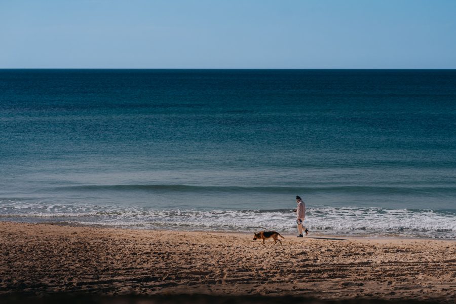 Homem passeando com cão na praia de Itaipu, Niterói